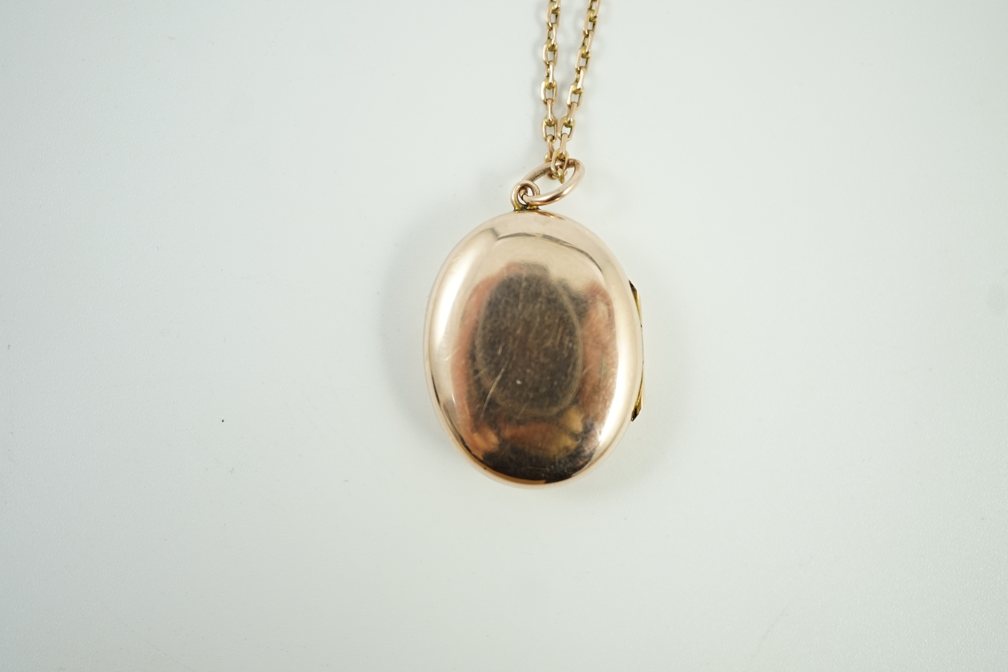 An Edwardian yellow metal and seed pearl set oval locket pendant, 25mm, on a 9ct chain, 47cm, gross weight 9.3 grams.